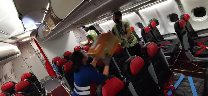 Two people passing a box in an aircraft
